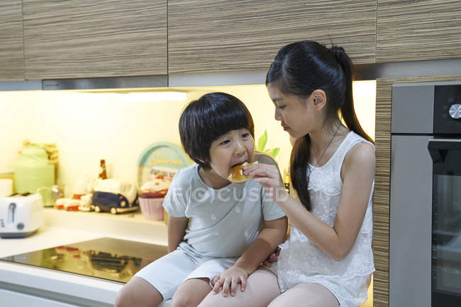 Счастливая молодая азиатская семья вместе едят на кухне — стоковое фото