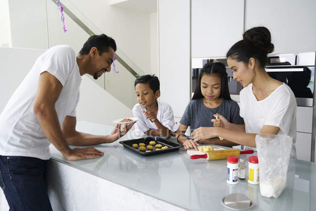 Familia asiática joven celebrando Hari Raya juntos en casa y cocinar platos tradicionales - foto de stock