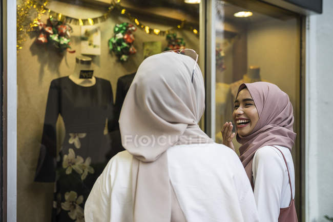 Duas senhoras muçulmanas janela de compras para roupas hari raya . — Fotografia de Stock