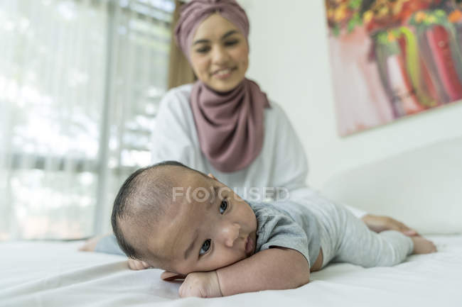 Mãe e bebê deitados na cama em casa — Fotografia de Stock
