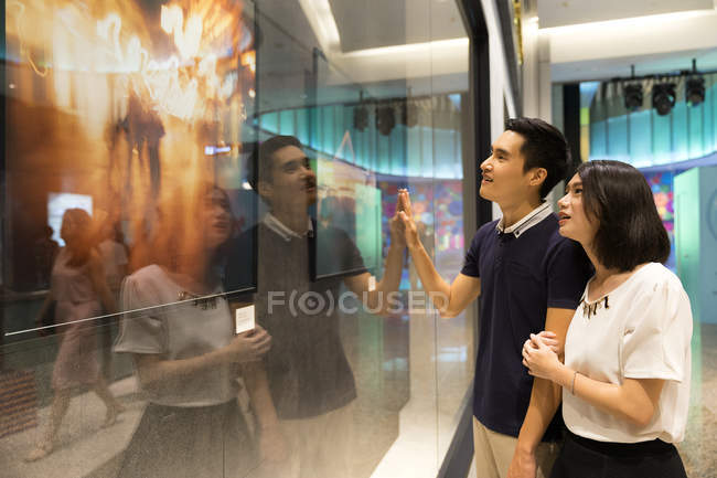 Young attractive asian couple together shopping and looking on tv screen — Stock Photo