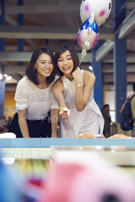 Amigos lanzando una moneda en un carnaval para ganar premios en Singapur - foto de stock