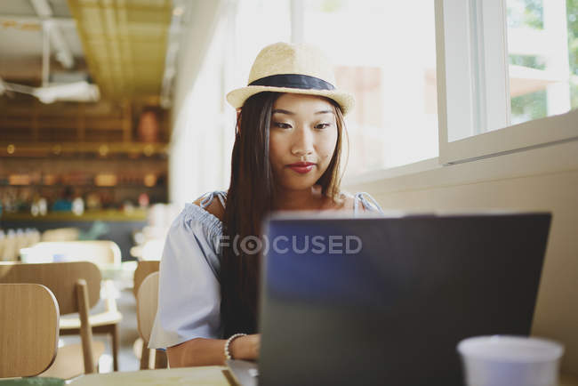 Hermosa joven asiática mujer usando laptop en café - foto de stock