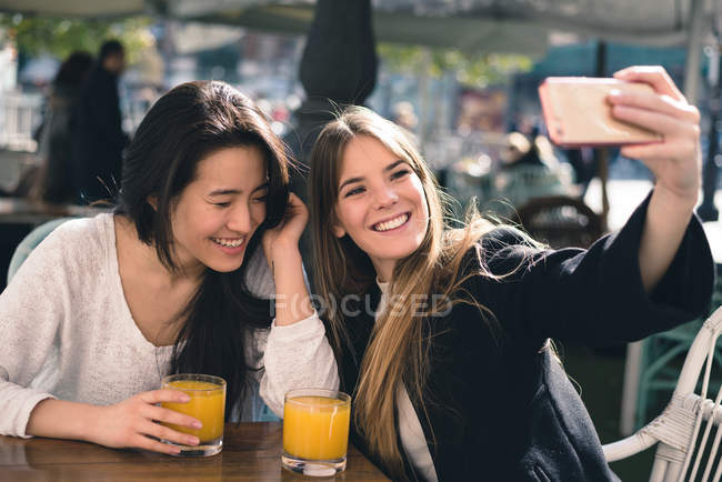 Дві красиві друзі-жінки, які беруть селфі в кафе — стокове фото