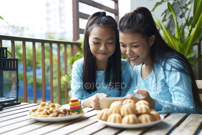 Dos hermanas celebrando Hari Raya juntas en casa - foto de stock