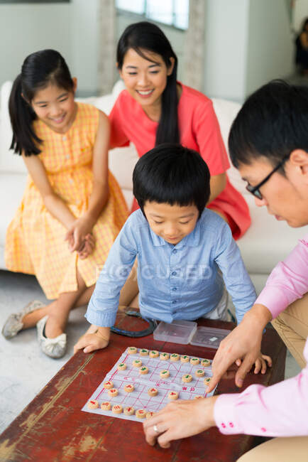 LIBERTAS Feliz familia asiática jugando en el tablero juego - foto de stock