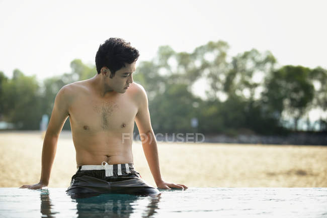 Jovem atraente asiático homem relaxante na piscina — Fotografia de Stock