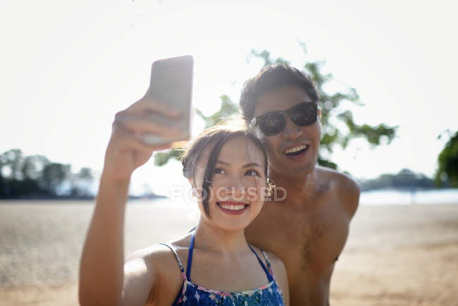 Young attractive asian couple taking selfie on smartphone — Stock Photo