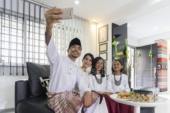Glückliche asiatische Familie feiert Hari Raya zu Hause und macht Selfie — Stockfoto