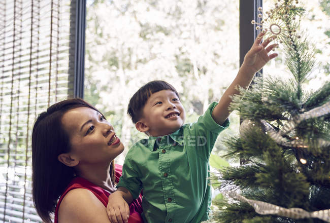 Happy asian family celebrating christmas together, mother and boy near fir tree — Stock Photo