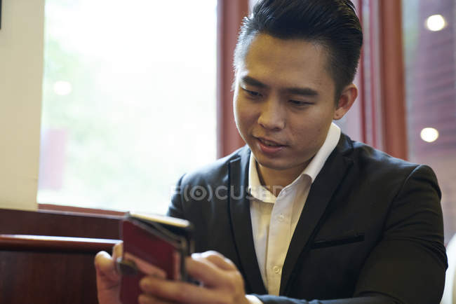 Young handsome male businessman using smartphone in office — Stock Photo