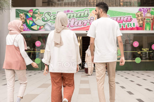 Tres amigos caminando hacia el centro comercial - foto de stock