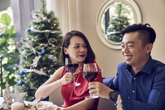 Happy young asian friends celebrating christmas together with wine — Stock Photo