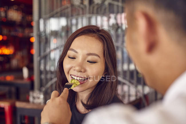 Молодая привлекательная азиатская пара, встречающаяся в кафе, мужчина кормит женщину — стоковое фото