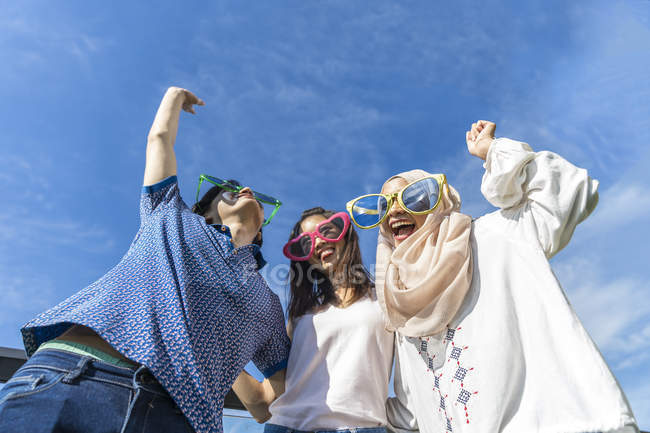 Группа друзей в смешных очках веселится против голубого неба — стоковое фото