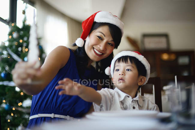 Madre e hijo pequeño celebrando la Navidad juntos en casa - foto de stock