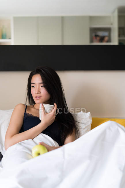 Chinesische junge und schöne Frau wacht morgens auf und frühstückt im Bett — Stockfoto