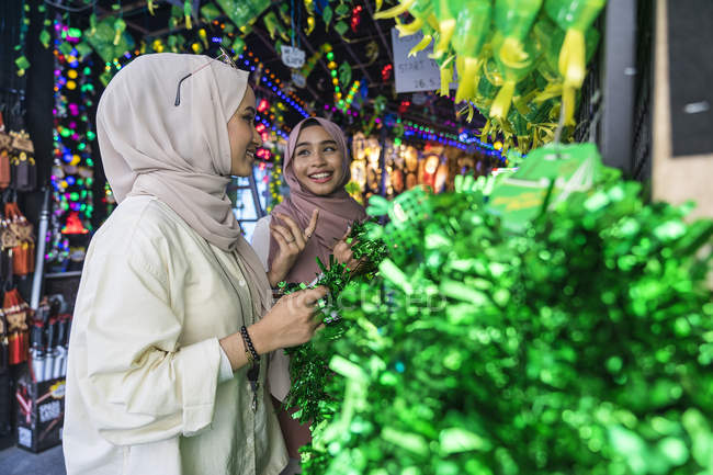 Two muslim ladies shopping for hari raya decorations. — Stock Photo