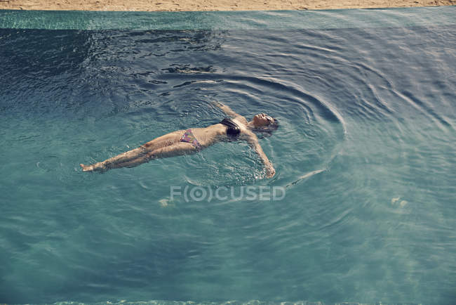 Bela jovem nadando de volta na piscina — Fotografia de Stock