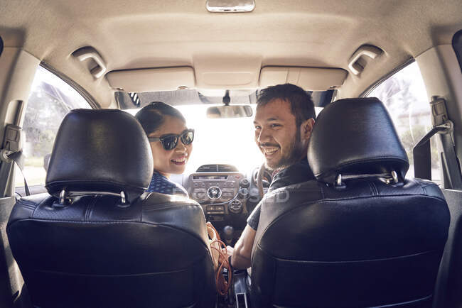 RILASCIO Sorridente giovane coppia in una macchina guardando la macchina fotografica — Foto stock