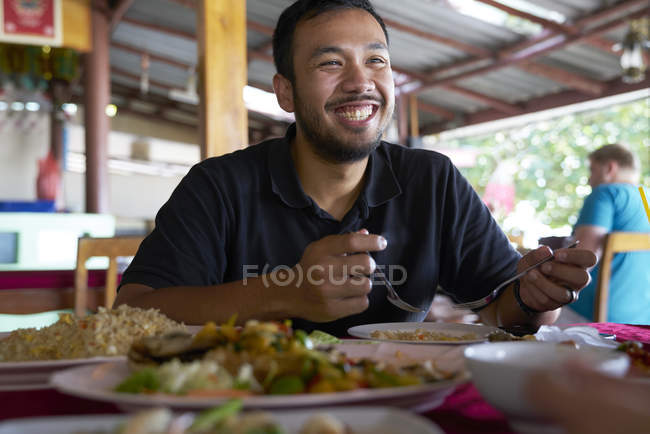 Молодой человек наслаждается едой в ресторане на Ко Чанг, Таиланд — стоковое фото