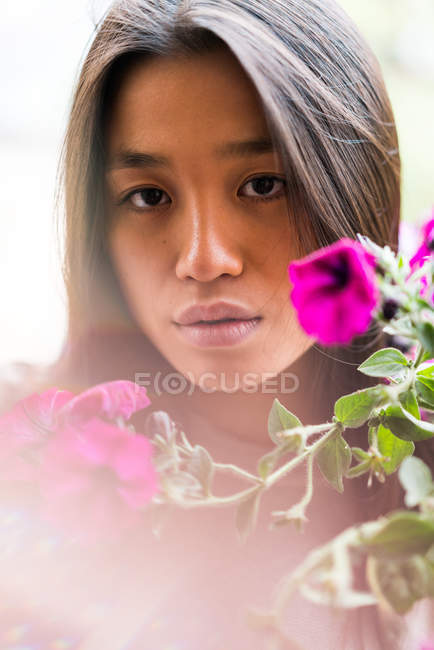 Cabello largo mujer china con flores mirando a la cámara - foto de stock