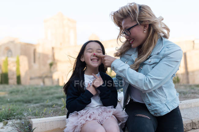 Retrato de jovem mãe feliz com sua filha se divertindo na cidade em um dia ensolarado . — Fotografia de Stock