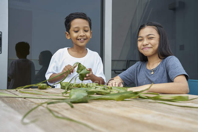 Jovem asiático irmãos celebrando hari raia juntos no casa e fazendo decorações — Fotografia de Stock