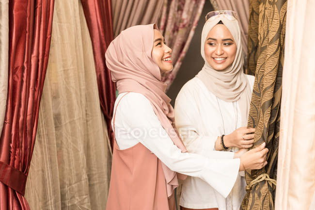 Dos musulmanas en una tienda comprando cortinas - foto de stock