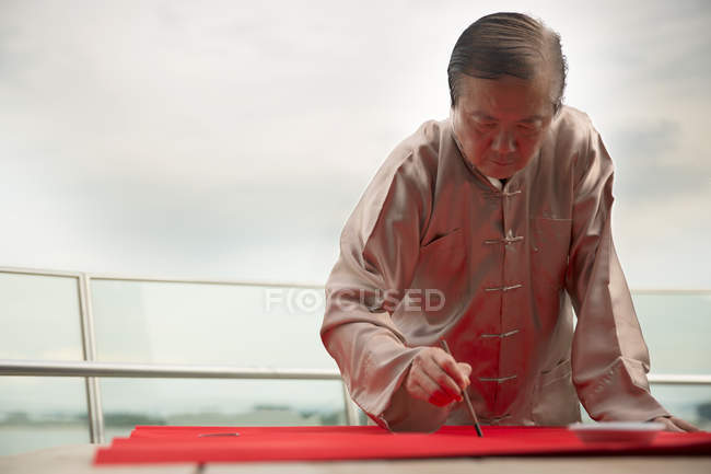 Idade asiático homem desenho caligrafia hieróglifos no chinês ano novo — Fotografia de Stock
