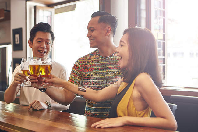 Feliz joven asiático amigos juntos en bar teniendo cerveza - foto de stock