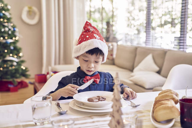 Little asian boy eating cake at christmas — Stock Photo
