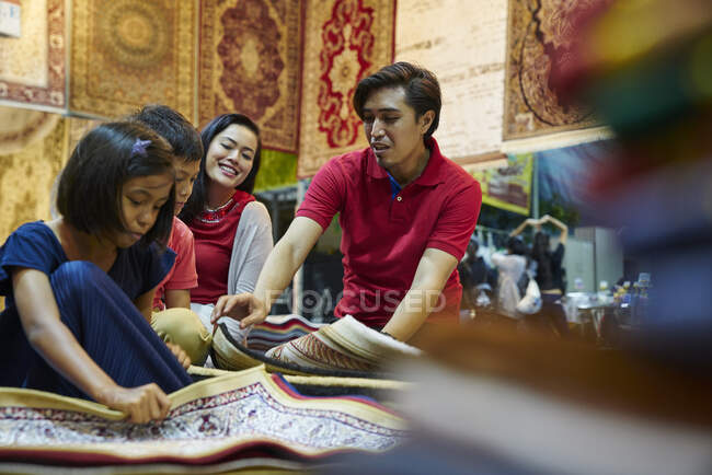 Молодая семья ищет ковры на Geylang Bazaar, Сингапур — стоковое фото