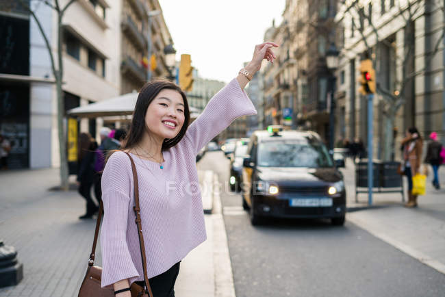 Young Chinese tourist woman flagging a cab in barcelona — Stock Photo