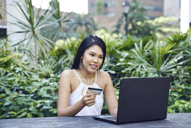 Красивая малайская леди делает онлайн покупку с помощью своей кредитной карты — стоковое фото