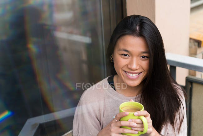 Mulher de cabelo longo sorrindo para a câmera e segurando café — Fotografia de Stock