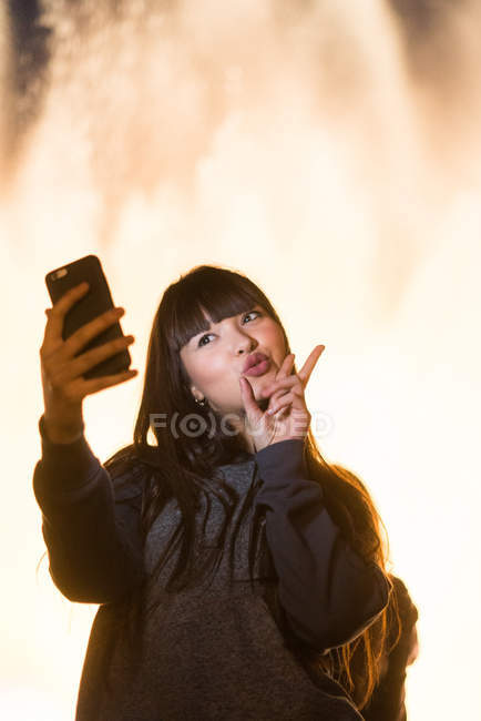 Junge eurasische Frau macht ein Selfie und gestikuliert — Stockfoto