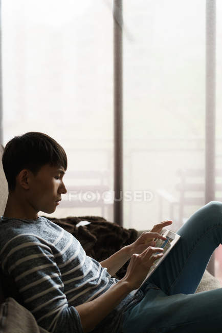 Young adult asian man using digital tablet at home — Stock Photo
