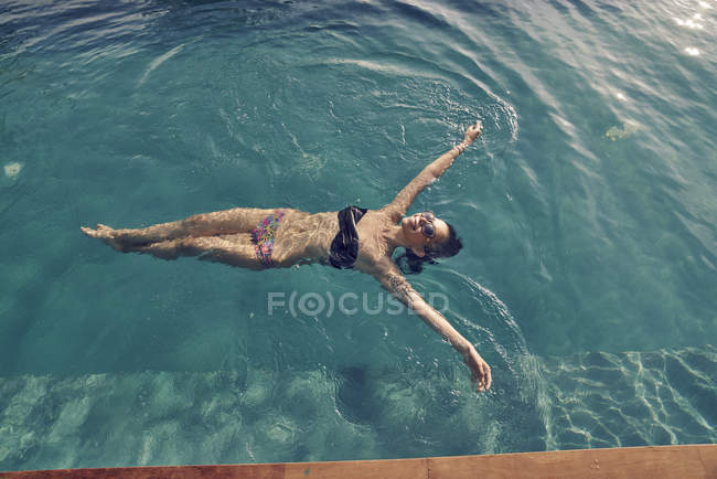 Belle jeune femme nageant sur le dos dans la piscine — Photo de stock