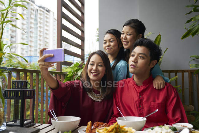 Young asian family celebrating Hari Raya in Singapore and taking selfie — Stock Photo