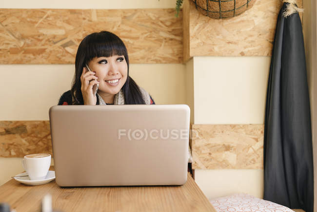 Young attractive asian woman using smartphone in cafe — Stock Photo