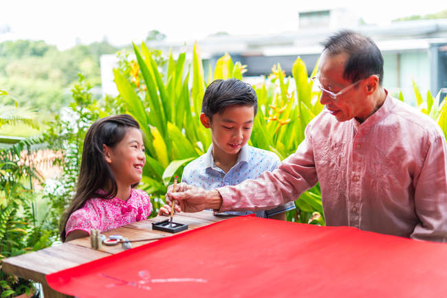 Felice famiglia asiatica insieme, nonno e nipoti che disegnano geroglifici — Foto stock