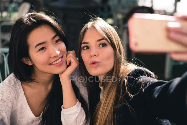 Two beautiful female friends taking selfie on smartphone — Stock Photo