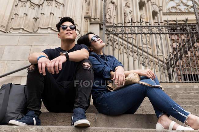 Young Chinese in sunglasses sitting together on steps — Stock Photo