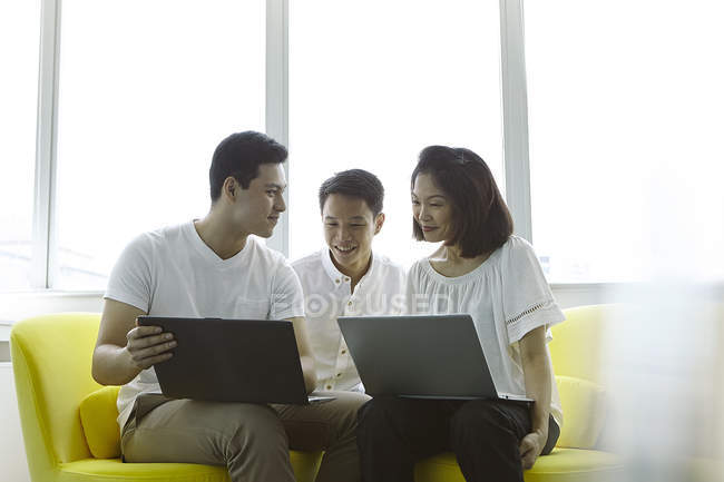 Jeunes gens d'affaires asiatiques travaillant avec des ordinateurs portables au bureau moderne — Photo de stock