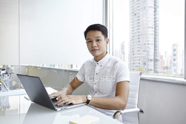 Jeune homme d'affaires asiatique au travail dans un bureau moderne — Photo de stock