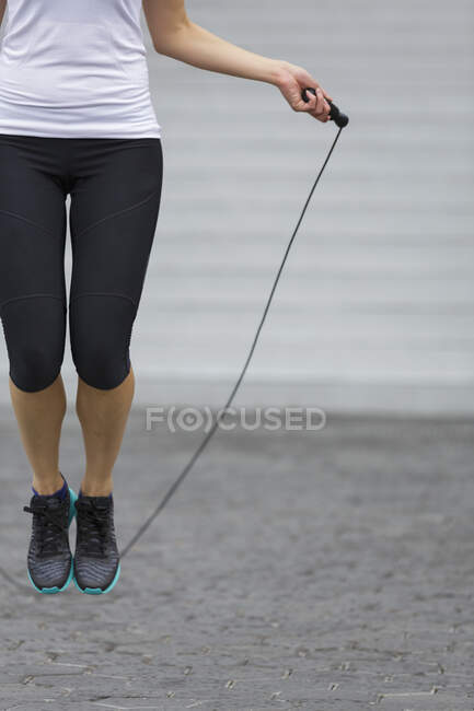 Uma jovem mulher asiática está se exercitando com salto de corda, ao ar livre em Cingapura — Fotografia de Stock