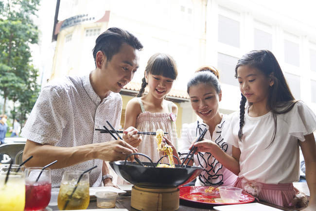Happy asian family eating noodles together in street cafe — Stock Photo