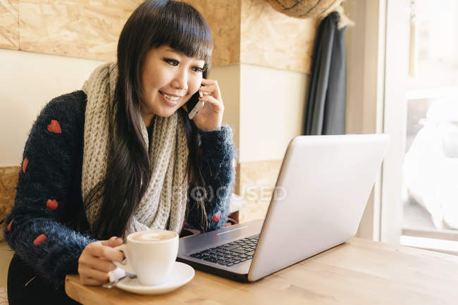 Jeune attrayant asiatique femme en utilisant smartphone dans café — Photo de stock