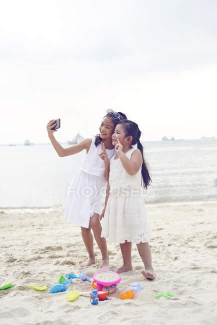 RELEASES Zwei kleine Schwestern verbringen Zeit zusammen am Strand und machen Selfie — Stockfoto